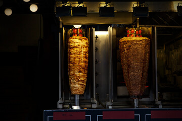 Traditional Turkish food Doner Kebab. Two rolls of chicken and beef meat are grilling on street.