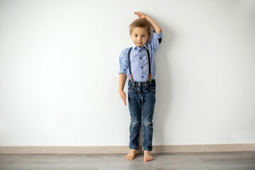 Little child, boy, measuring height against wall in room