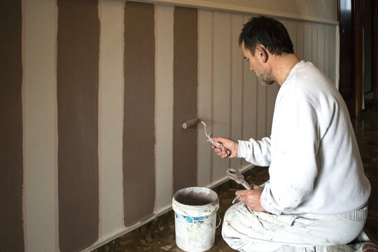 Painter painting stripes on a wall with a roller