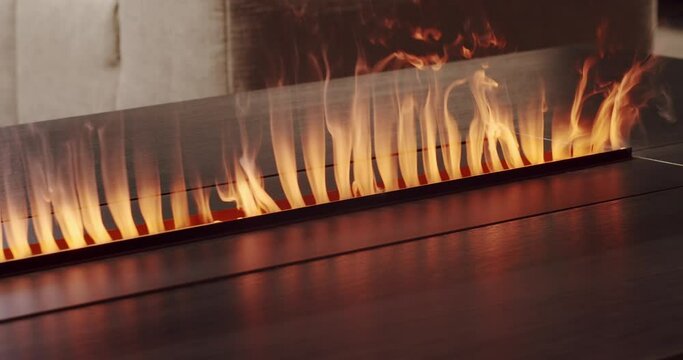 Side view on electric fireplace with artificial sparkling flame, decor for the interior, orange fire flame. Close-up artificial electronic fireplace burning with smoke fire. Bio fireplace burn.