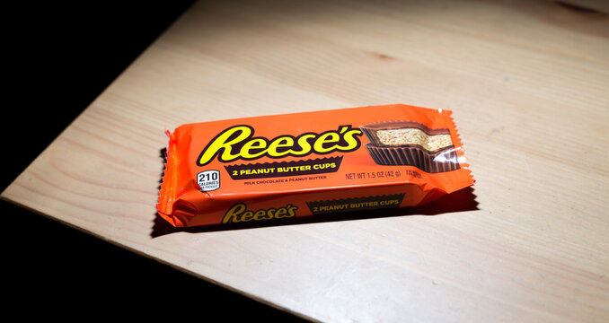 Trenton, MO / United States of America - August 29th, 2020 : Reese's Peanut Butter Cups in package on the corner of a wooden coffee table.  Standard size 2 pack of name brand candy on counter top.