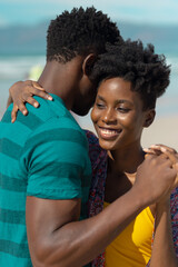 Fototapeta premium Close-up of smiling african american young woman with short hair dancing with boyfriend at beach