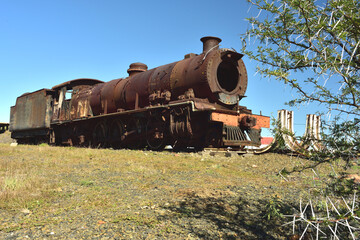 An old rusted steam locomotive that is parked in its last resting place