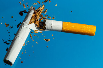 Broken cigarette on blue background. Stop smoking concept photography