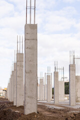 construction of an industrial building site with a line of concrete columns and reinforcing steel