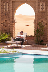 Joven descansando en tumbona de hotel junto al desierto. Marruecos.