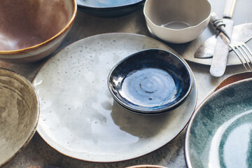 Variety of ceramic tableware, plates, bowls, glazed dishes and cutlery
