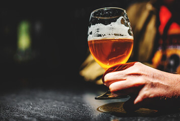 man holds a glass of beer in his hand at the bar or pub
