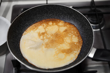 Frying delicious crepe on pan in kitchen, closeup