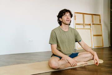 White man wearing shorts sitting on mat during yoga practice