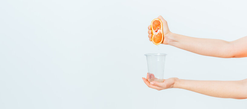 Female hands squeezing juice from fresh grapefruit