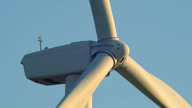Close up shot of wind mills turbine rotating by the wind and generating renewable green energy. Closeup of a wind turbine during golden hour sunset. Energy alternative and environment ecology.