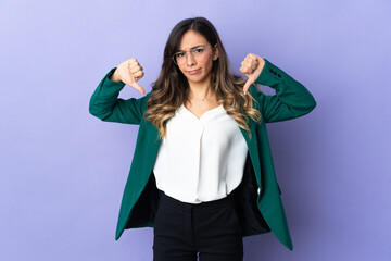 Young caucasian woman isolated on purple background showing thumb down with two hands