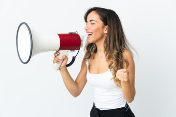 Young caucasian woman isolated on white background shouting through a megaphone to announce something in lateral position