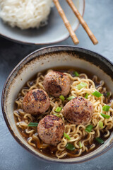 Bowl of ramen noodles with fried meatballs in miso broth, close-up, vertical shot, selective focus