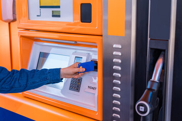 Detalle de brazo de un hombre caucásico, en la maquina de pago en la gasolinera, pagando en...
