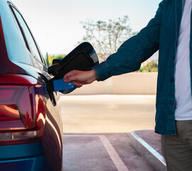 Detalle de brazo de un hombre caucásico, con la tarjeta bancaria, repostando en la gasolinera.