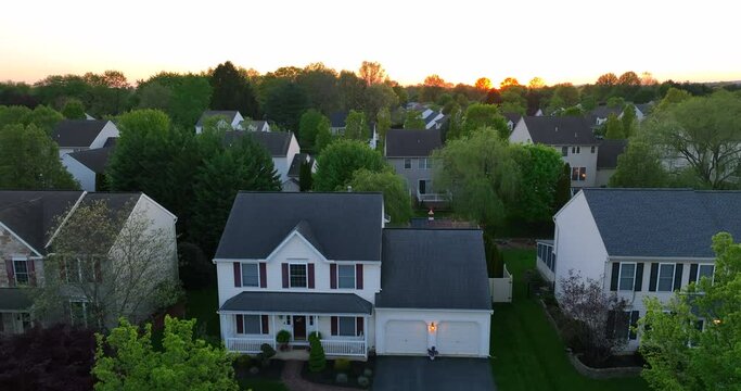 Aerial rising shot of one family home. Neighborhood in spring. Sunset over houses in America.