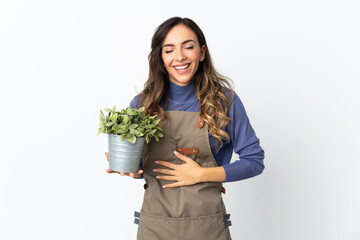 Gardener girl holding a plant isolated on white background smiling a lot