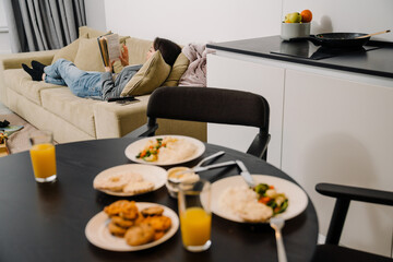 Young asian woman lying and reading book on sofa at home