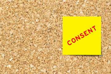 Yellow note paper with word consent on cork board background with copy space