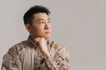 Asian puzzled military man wearing uniform posing on camera