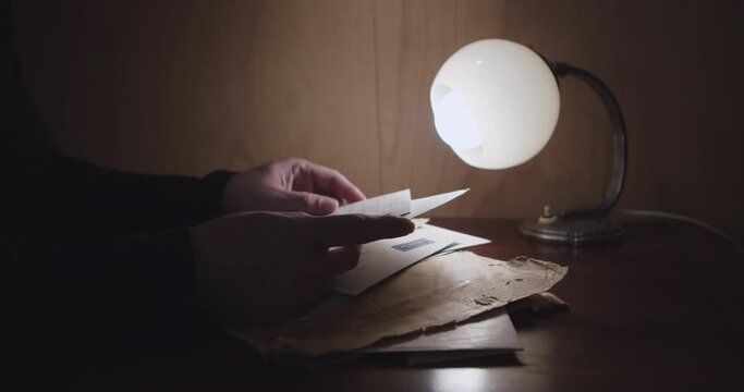A person walks through a pile of letters and correspondence illuminated by a small lamp