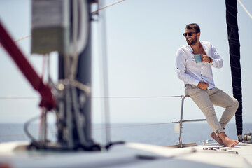A young handsome barefoot male model is in a good mood while enjoying a photo shooting on a yacht...