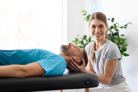 Modern rehabilitation physiotherapy woman worker with man client neck treatment