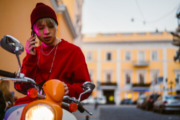 Asian boy talking on cellphone while sitting on scooter