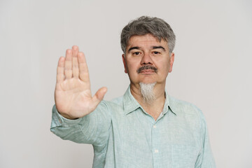Fototapeta premium Mature man with grey beard showing stop gesture at camera