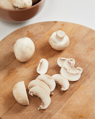 Sliced champignon mushrooms on wooden cutting board