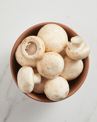 Overhead view of champignon mushrooms in brown bowl