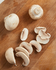 Sliced champignon mushrooms on wooden cutting board