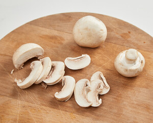 Sliced champignon mushrooms on wooden cutting board