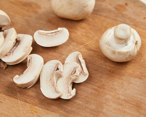 Sliced champignon mushrooms on wooden cutting board
