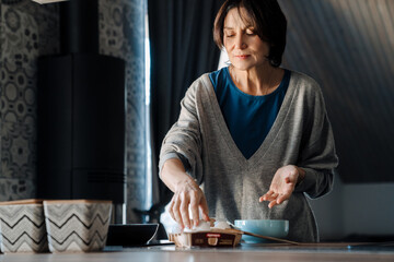 White mature woman making scrambled eggs while cooking in kitchen