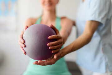 Modern rehabilitation physiotherapy woman worker with woman client using ball
