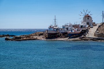 Greece. Koufonisi island, Cyclades. Windmill, shipyard for wooden fishing boat, sea, blue sky.