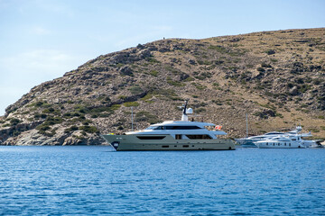 Fototapeta na wymiar Yacht, luxury motorboat moored at a secluded beach, Kythnos island Greece. Summer vacation