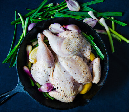 Uncooked chicken with vegetables and lemon in a cast iron skillet 
