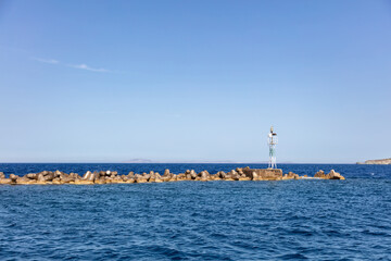 Fototapeta premium Beacon at breakwater concrete block at Ermoupolis city port, Syros island, Cyclades Greece.