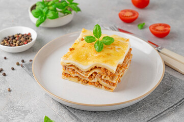 Slice of Lasagna bolognese with meat sauce and bechamel with melted cheese on top and fresh basil. Italian cusine. Copy space.