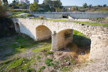 Fototapeta na wymiar Medieval Venetian Stone Bridge in Cyprus, Juxtaposed with Modern Roadway Bridge