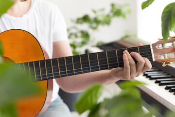 Women's hands play the guitar. Fingers pinch the strings on the fretboard. Home music making,...