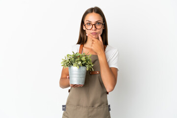 Gardener girl holding a plant over isolated white background thinking