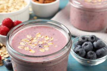 Tasty berry smoothie with oatmeal on light blue table, closeup