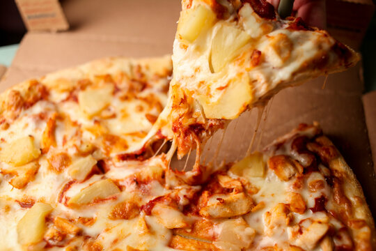 a piece of very tasty pizza with pineapple slices and cheese, close-up. juicy tasty pizza close-up