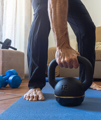 Closeup of man grabing kettlebell during home workout exercises