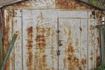 one old gray brown rusty metal garage with closed gates on the street